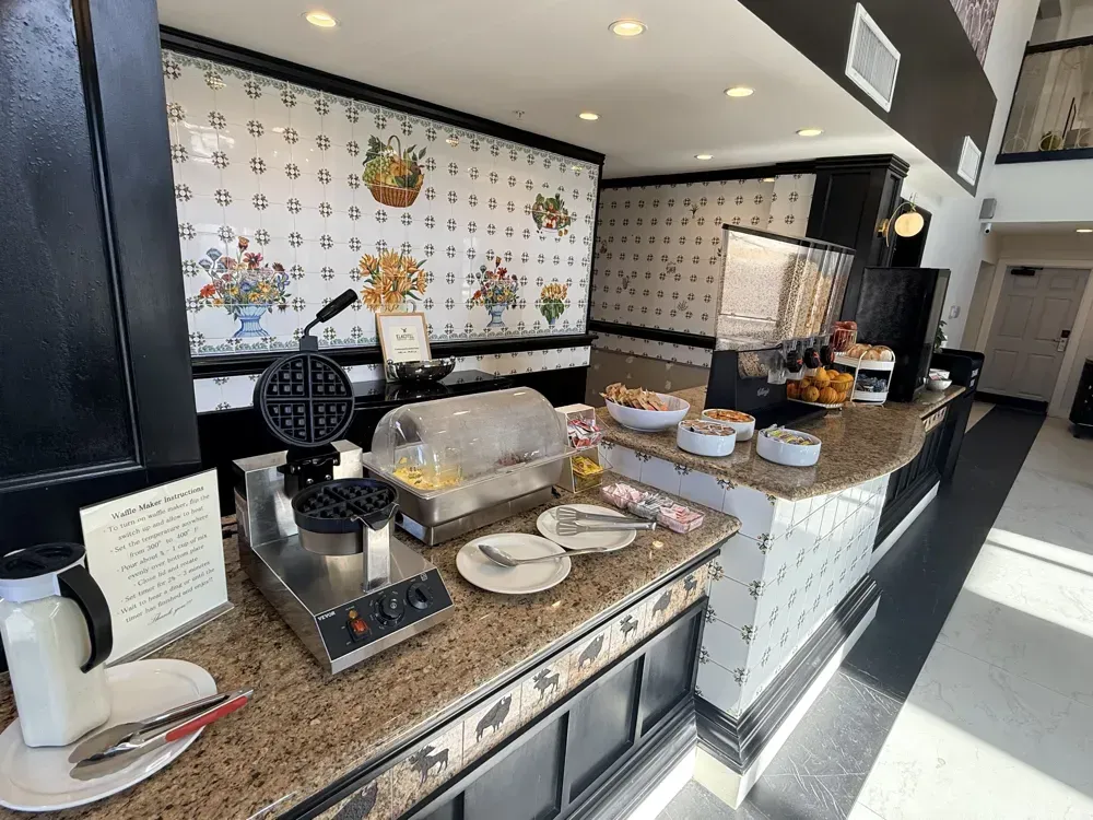 The breakfast buffet counter with waffle makers, cereal and fresh fruit