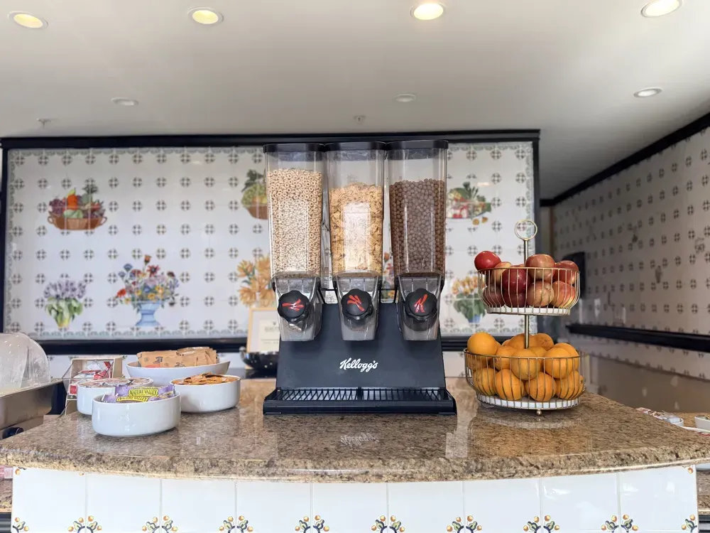 Cereal dispensers and a bowl of fresh apples and oranges
